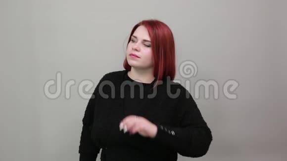 年轻的红头发的胖女人穿着黑色毛衣聪明的女人想手捂着头视频的预览图