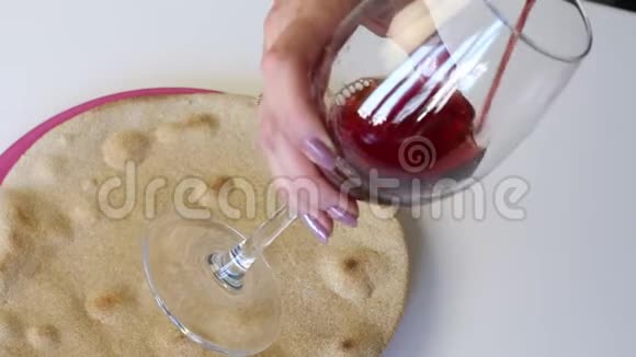 桌子上有一个盘子上面有一个烤圆的新鲜蛋糕在她的上方一个女人拿着一杯把红酒倒进里面他穿上了视频的预览图