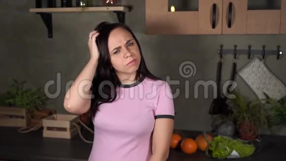 年轻女子在厨房里用手挠头的肖像成年迷人女性思考什么视频的预览图