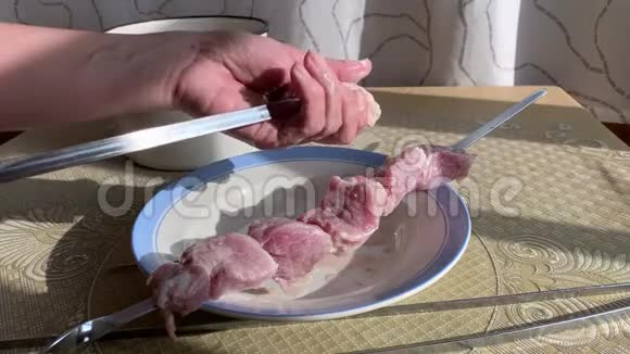 一个女人把肉串在肉串上以便做烤架在明火上粉碎烧烤准备和腌制视频的预览图