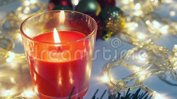红色的圣诞蜡烛在桌子上燃烧上面有节日的花环和松树的装饰品和球视频的预览图