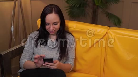 自信快乐的年轻女性躺在家里的沙发上从上面穿着休闲装的年轻迷人女子视频的预览图