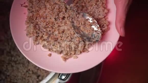 准备好的荞麦倒在粉红色的盘子里在家里用棕色的木桌做谷类食品倒在框架的中央视频的预览图