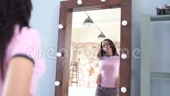 一个英俊的女人照镜子一位年轻女性在现代卧室镜子中的侧景视频的预览图