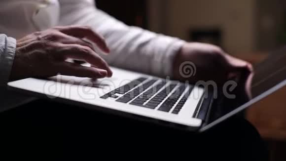 在黑暗的房间里专注的商人在笔记本电脑键盘上打字视频的预览图