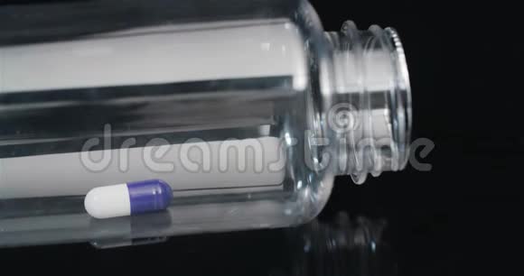 在黑色背景下旋转的小瓶中的单个医疗丸视频的预览图