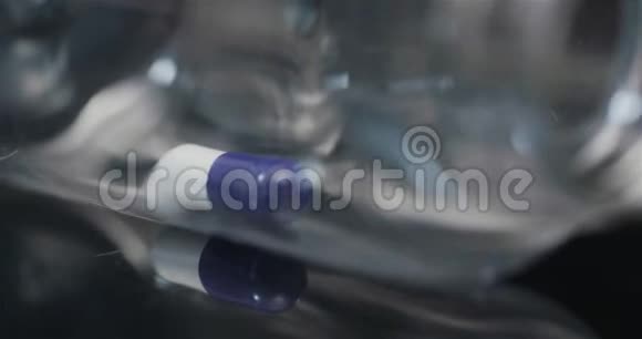 在黑色背景上旋转的小瓶子中的单个医疗药丸视频的预览图