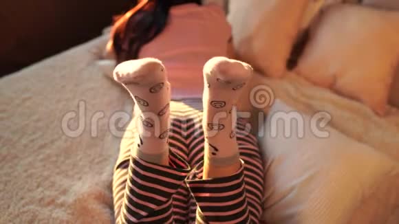 年轻女子穿着睡衣躺在床上的后视镜早睡在大床上的成年女士穿着袜子晃着腿视频的预览图