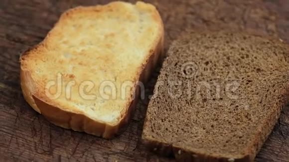 两片烤黑麦和白面粉面包放在棕色木板上视频的预览图