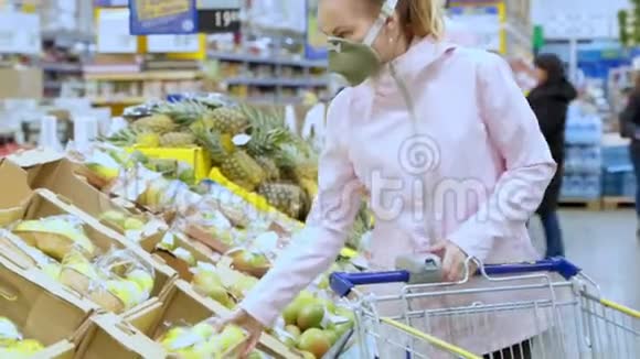 女人欧洲外观在一个保护性呼吸医疗口罩在一个市场一个商店选择蔬菜和水果视频的预览图