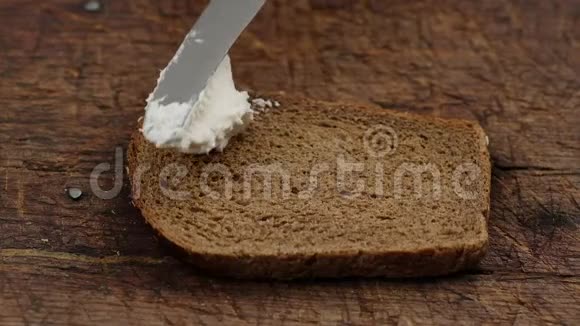 手拿刀在烤黑麦面包上抹上白干酪视频的预览图