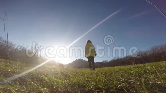 一个女孩走在山的背景下的小径上阳光灿烂视频的预览图