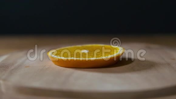 合上切片橙果落在乡村木桌上的黑色背景慢镜头视频的预览图
