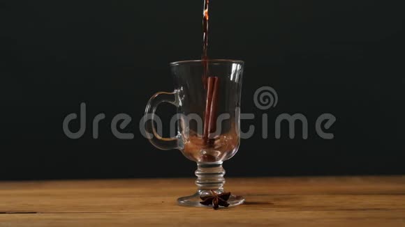 在黑色背景的木桌上将热覆盖的葡萄酒倒入爱尔兰咖啡杯中视频的预览图