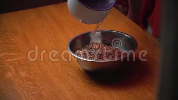 荞麦煮饭前倒水在家里用棕色的木桌视频的预览图