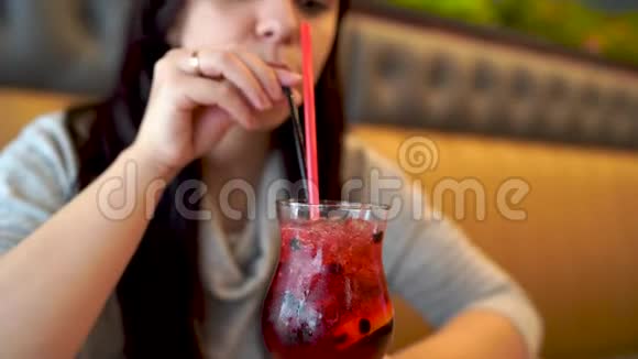 女人在咖啡馆喝鸡尾酒成年女士坐在餐桌上一边用吸管啜饮新鲜水果饮料视频的预览图