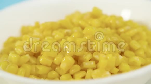在白色盘子里的旋转台上炒出甜黄的玉米种子视频的预览图