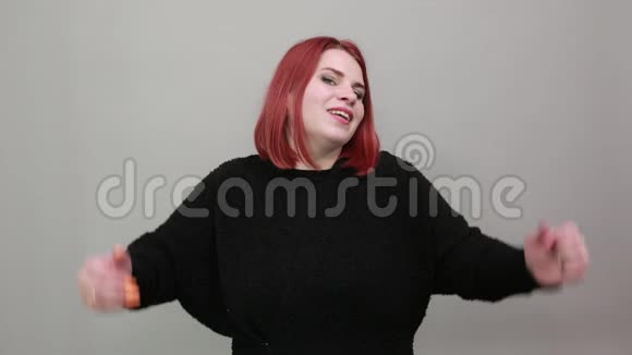 年轻的红头发胖女人穿着黑色毛衣高兴的女人高兴举起双手视频的预览图