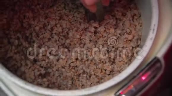 将荞麦拌入平底锅中在家里用棕色的木桌煮麦片视频的预览图
