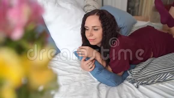 早上穿着睡衣躺在床上抱着枕头的年轻漂亮女人的肖像成人女士休息特写视频的预览图