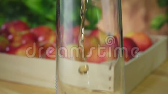 果汁倒在苹果旁边的一个罐子里放在绿色植物的背景上视频的预览图