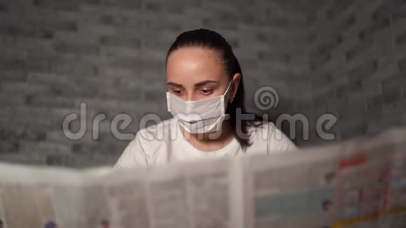 一个带着医疗面具的女人她听到的关于冠状病毒的消息来自报纸冠状病毒的流行视频的预览图