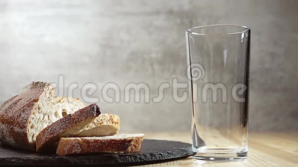 牛奶被倒入玻璃和新鲜面包中慢动作视频的预览图