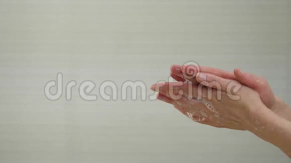 一个女人在特写镜头中用白色肥皂泡洗手示范洗手以防病毒视频的预览图