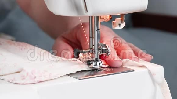 密切观察缝纫过程在冠状病毒期间女性用手在缝纫机上用棉织物缝制医用口罩视频的预览图