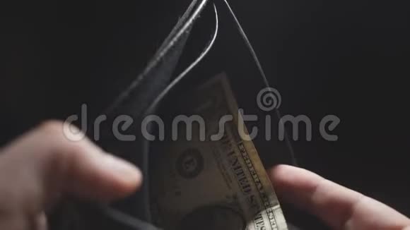 一个男人的手在黑暗的背景上特写钱包里有一美元预算和费用视频的预览图