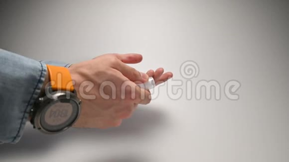 穿着一件蓝色牛仔衬衫一条带有黄色带子的紧身男性手和一只手表用一种消毒剂喷洒一种防腐剂来治疗视频的预览图