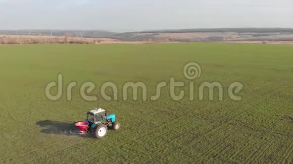拖拉机在绿田中播撒人工肥料农民用氮肥和钾肥耕地视频的预览图