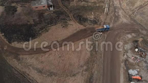 一辆空自卸卡车沿着土路行驶的鸟瞰图建筑工作和处置的概念视频的预览图