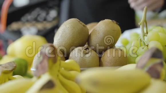 在杂货店货架上摆放的猕猴桃果实像一个面目全非的人把一个放进购物篮然后离开视频的预览图