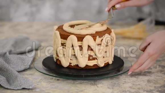 在面包店做蛋糕的女孩面包师把奶油挤到蛋糕层上视频的预览图