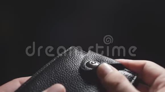 一个男人的特写镜头他的手在黑暗的背景上打开钱包视频的预览图