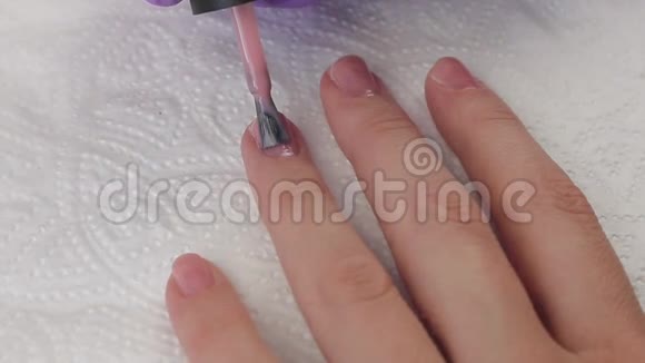 年轻女人用天然的粉红色凝胶基涂指甲指甲修指甲双手合拢视频的预览图