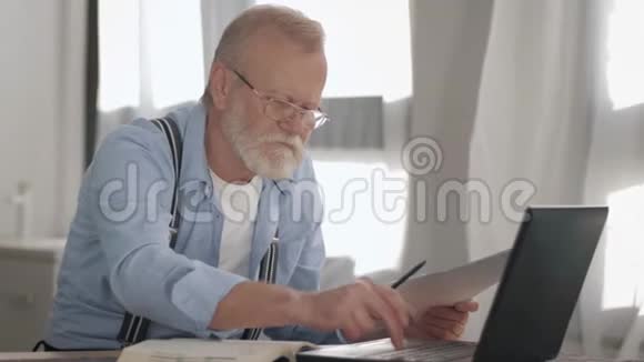 年长的祖父戴着眼镜戴着视力眼镜在笔记本电脑上工作并计算出家庭支付的费用视频的预览图