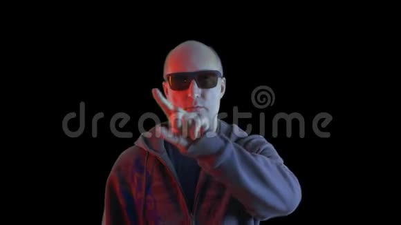 戴黑色太阳镜的秃头男子用手指在屏幕前相机上指指点点用手指在黑色上合上人的屏幕视频的预览图
