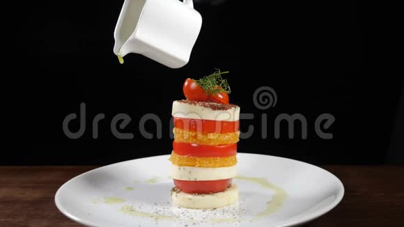 在马扎里拉沙拉上倒入橄榄油黑色背景上的食物片段意大利辣椒色拉和视频的预览图