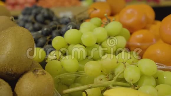 在杂货店里特写新鲜美味的绿色葡萄猕猴桃和橘子美味健康的食物躺在上面视频的预览图