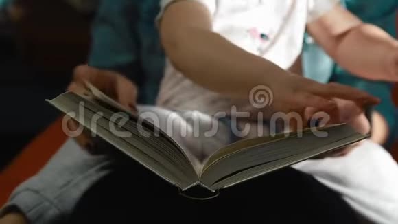 妈妈抱着一个孩子正在玩一本厚厚的书合上视频的预览图