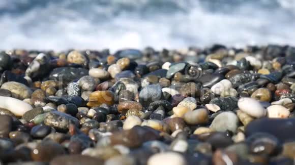 海滩上的卵石在大海的背景下从石头到海浪的平稳过渡乔治亚州的夏季海滩宏观视频的预览图