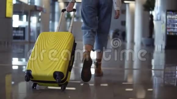 时尚女性带着手推车走黄色的箱子走在空的机场细长的女性腿和中轮的低半视图视频的预览图