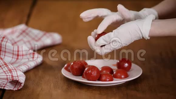 橡胶手套的糕点厨师做草莓球为蛋糕做果冻配料视频的预览图