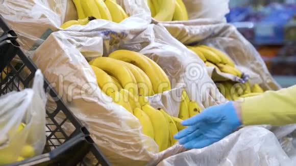 戴着医用手套的女性在杂货店拿香蕉视频的预览图