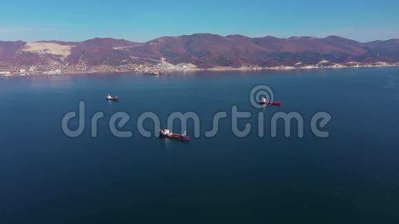 从空中俯瞰船只在平静的蓝色海面上漂流到丘陵海岸视频的预览图