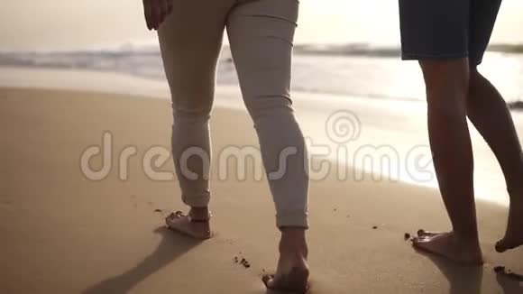 在海滩上赤脚行走的一对夫妇他们在一起在潮湿的沙滩上留下脚印视频的预览图