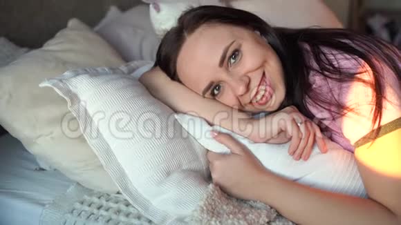 穿着睡衣睡在床上的漂亮年轻女人迷人的女性躺着看镜头的肖像视频的预览图