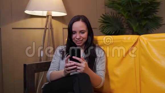 自信快乐的年轻女性躺在家里的沙发上从上面穿着休闲装的年轻迷人女子视频的预览图